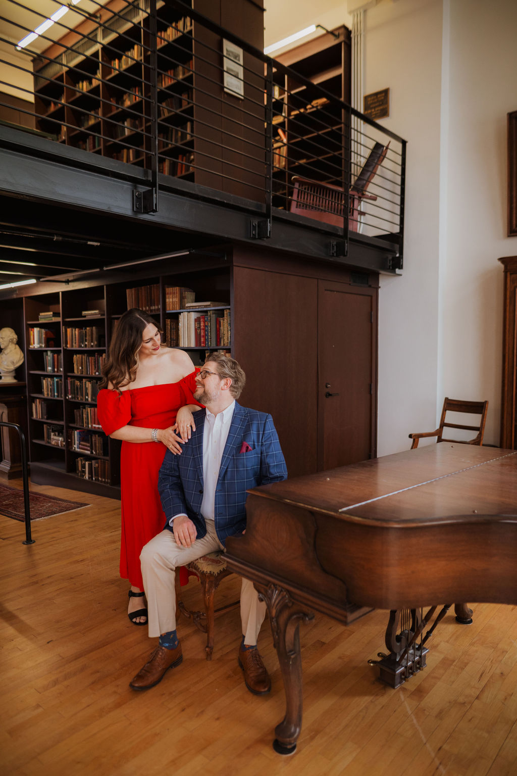 Margaret stands next to John, who is seated at a beautiful antique brown wood grand piano.